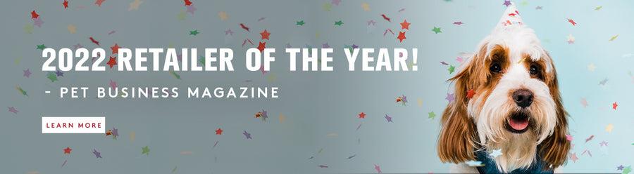 A long haired dog with white and brow hair with a party hat on, with confetti falling around it. We are the 2022 Retailer of the year - pet Business Magazine. Learn More